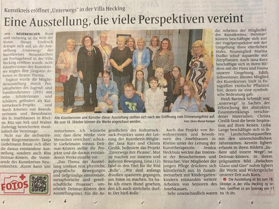 Ein Zeitungsausschnitt zeigt ein Gruppenfoto von etwa fünfzehn Personen, vermutlich den beteiligten Künstlern und Künstlerinnen, die lächelnd vor einer Wand mit Kunstwerken stehen. Der begleitende Artikel berichtet von der Eröffnung der Ausstellung „Unterwegs“ im Kunstkreis Villa Hecking.