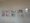 Fünf gerahmte, bunte abstrakte Bilder hängen in einer Reihe an einer weißen Wand. Die Kunstwerke zeigen verschiedene farbenfrohe Zeichnungen und Malereien und sind an einer Drahtschiene befestigt.
